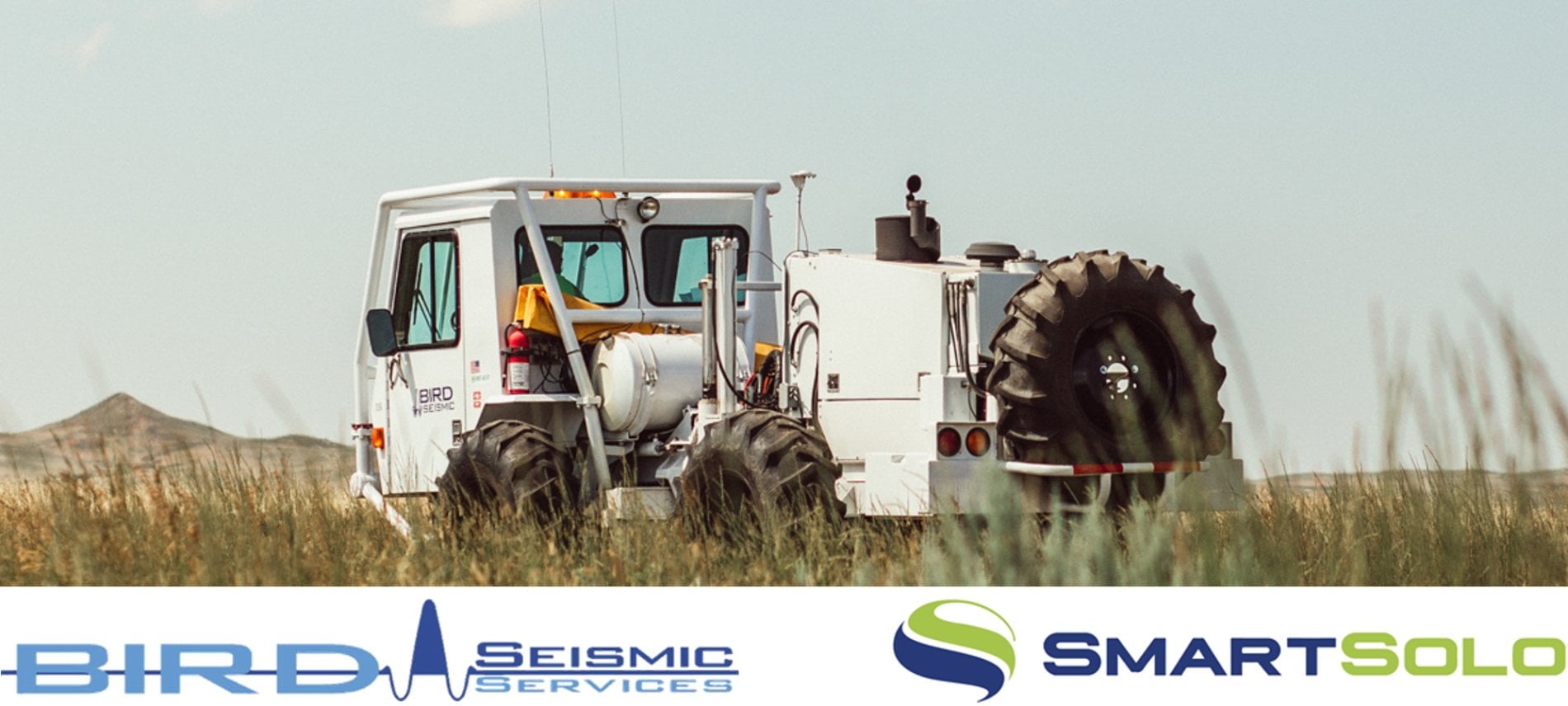 A white seismic vibrator truck with "BIRD SEISMIC SERVICES" logo in a field, with "SMARTSOLO" logo below.