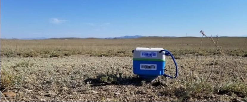 SmartSolo seismometer node deployed in a dry, grassy field under a clear blue sky for seismic activity monitoring and geophysical exploration.