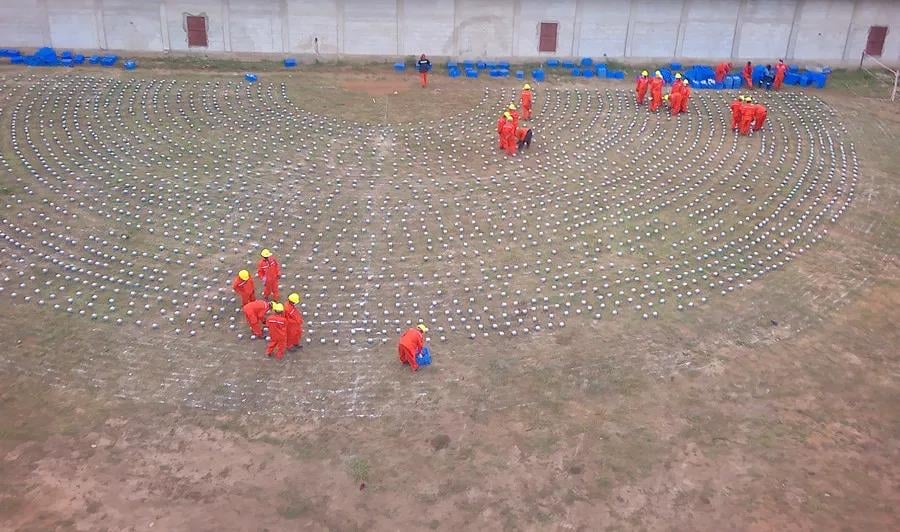 Workers in orange suits and yellow hard hats deploy thousands of SmartSolo nodes for a large-scale seismic survey.