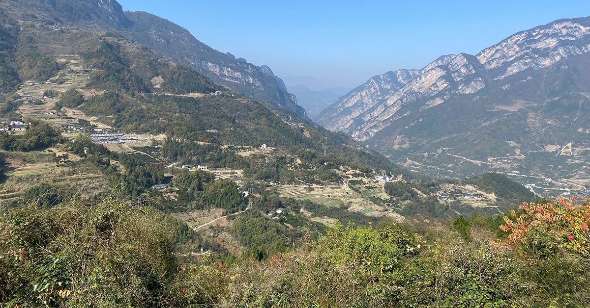A panoramic view of a mountainous landscape with terraced fields and scattered buildings, ideal for seismic survey and geological engineering.
