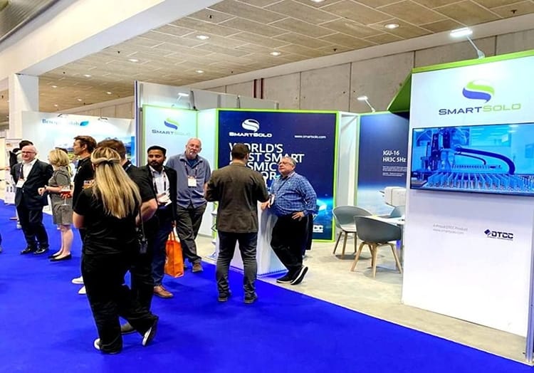 Attendees gather at the SmartSolo booth featuring "World's Smartest Seismic Sensor" and KGU-16 nodes for seismic survey.