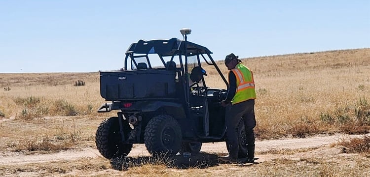 Two people with a utility vehicle deploying SmartSolo nodes for geophysical exploration in a field.