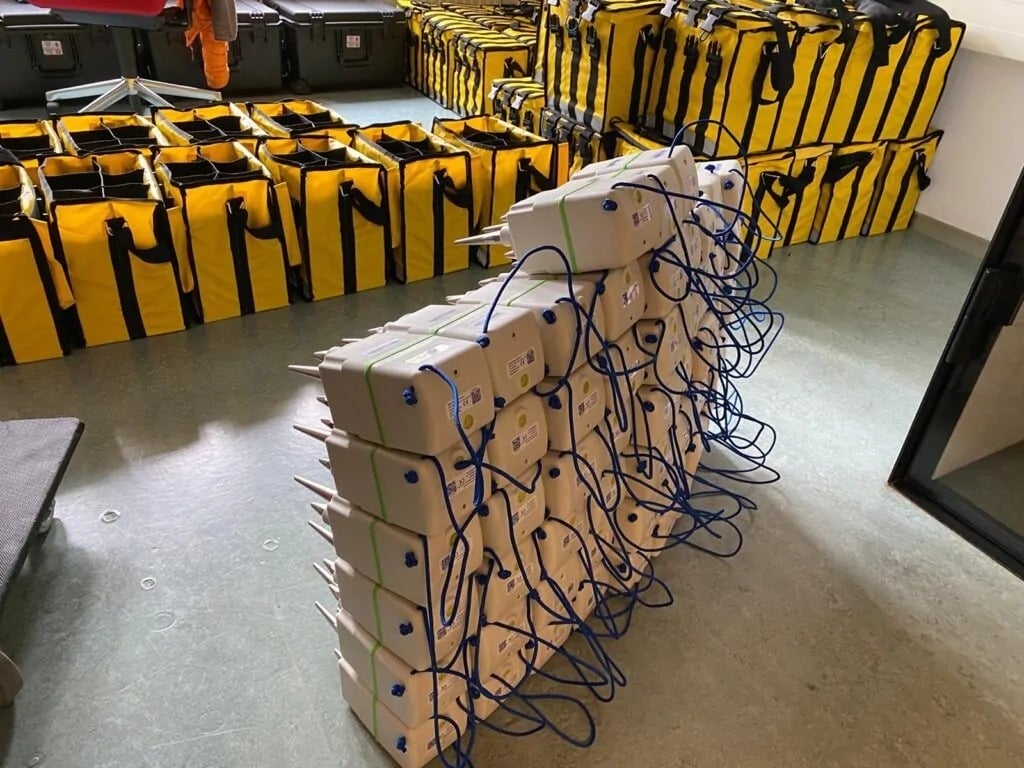 A large stack of SmartSolo seismometers with blue cables, ready for seismic survey and geophysical exploration.