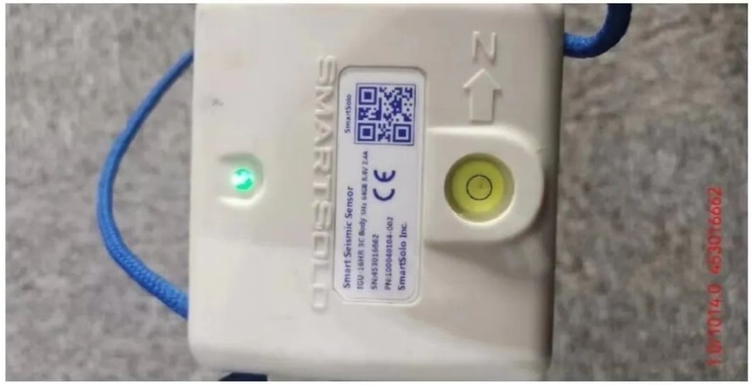 Close-up of a SmartSolo seismic sensor node with a QR code and level bubble.